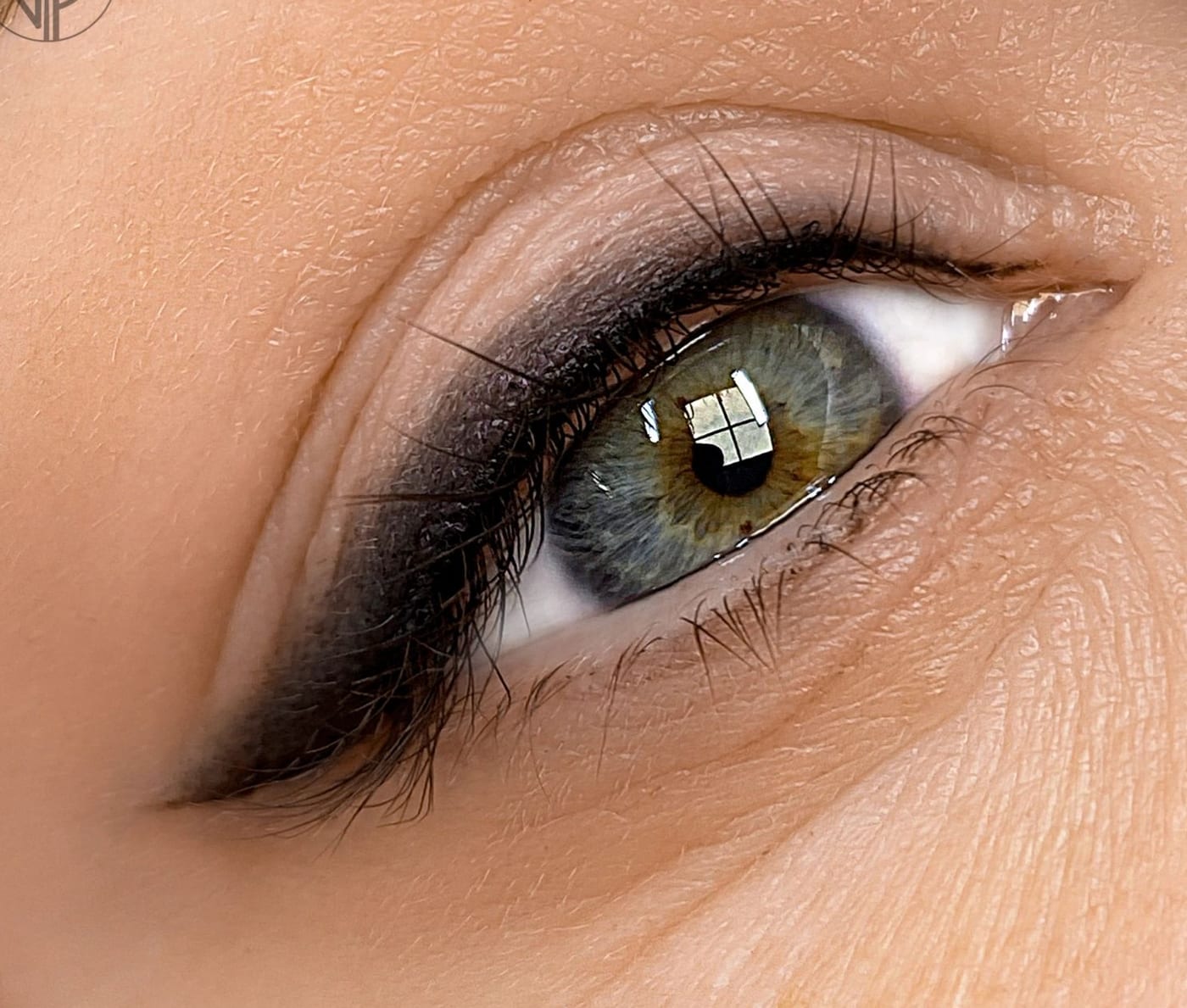 Grönt öga i närbild med mjukt skuggad soft eyeliner längs fransraden